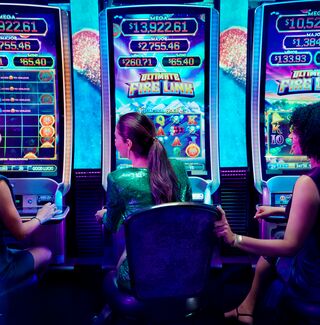 Group of female friends playing slot machines next to each other in a casino.